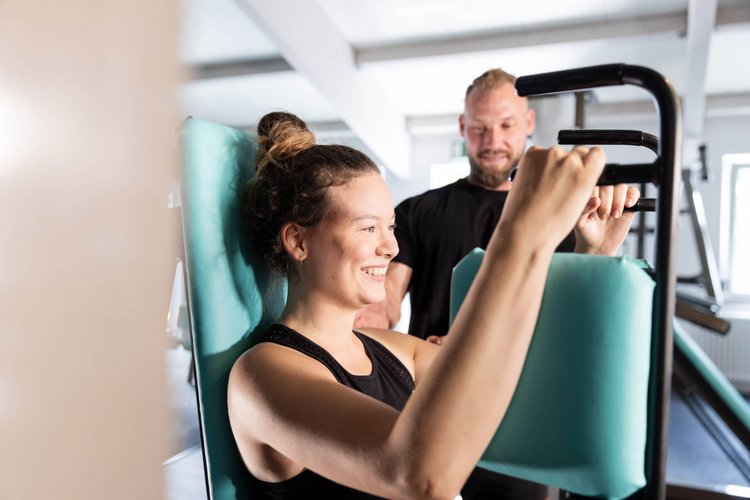 Tobi's Gym Butterfly Press Sportlerin und Trainer beim Oberkörpertraining in Tobi's Gym